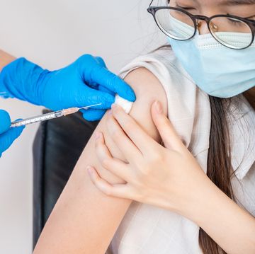 close up of doctor or nurse giving shot of covid19 vaccine to a patient's shoulder