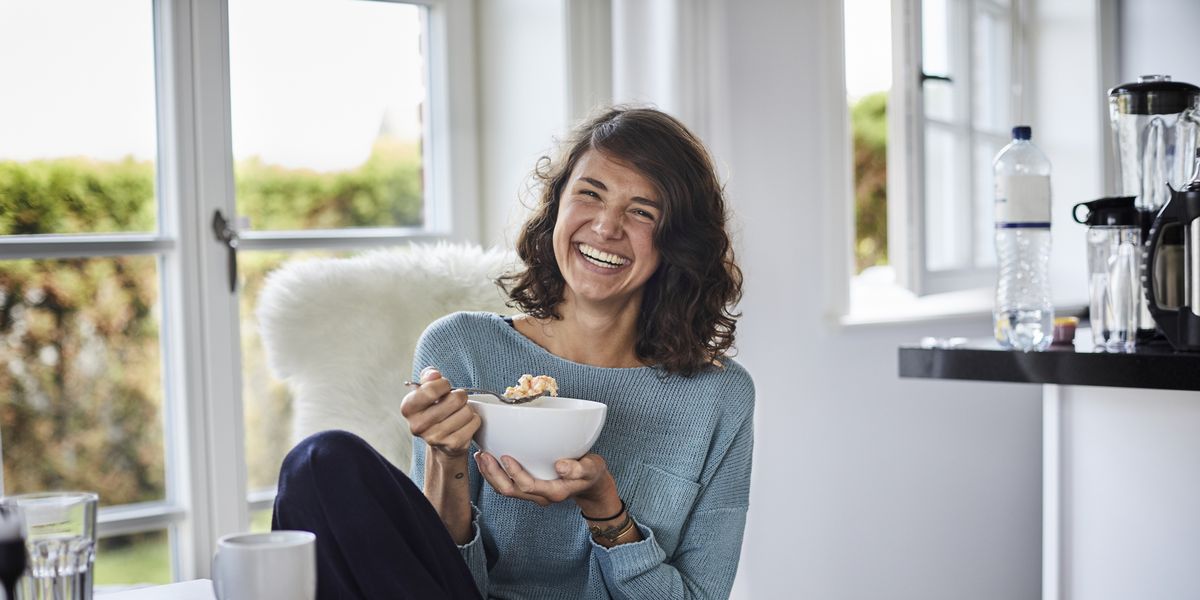 happy woman having breakfast at dining table