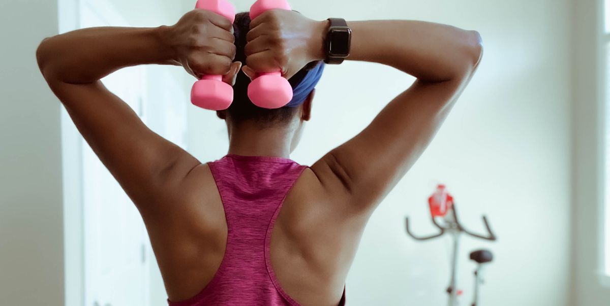 rear view of woman holding dumbbells behind head