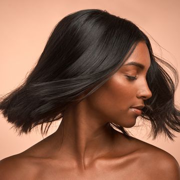 shot of a young attractive woman tossing her hair against a brown background
