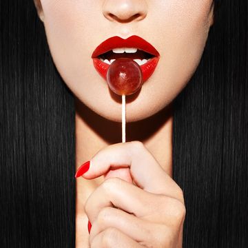 woman with red lips holding lollipop